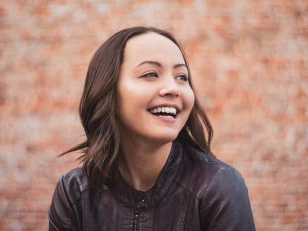 Senior portrait of girl laughing in front of brink wall