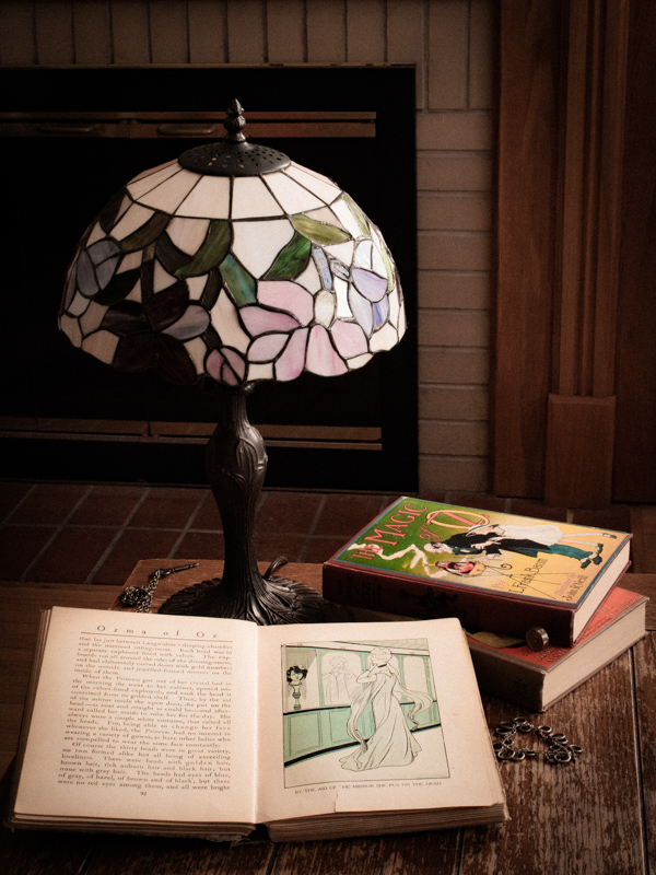 Antique lamp and books on a table in front of a fireplace