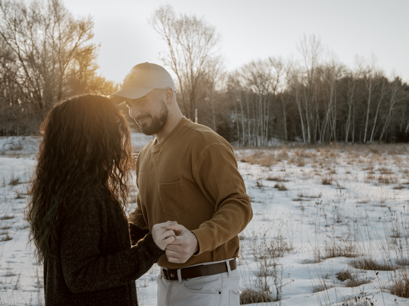 Candid shot of couple dancing in field with snow on ground